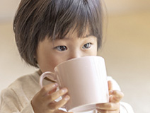 子どもがマグカップを持って飲んでいる